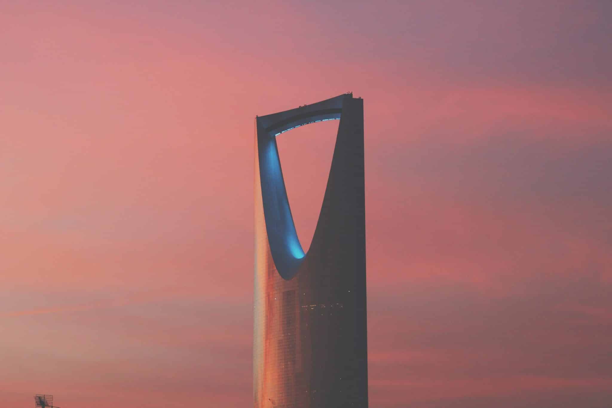 Silhouette of Kingdom Centre Tower in Riyadh against a pink sunset sky