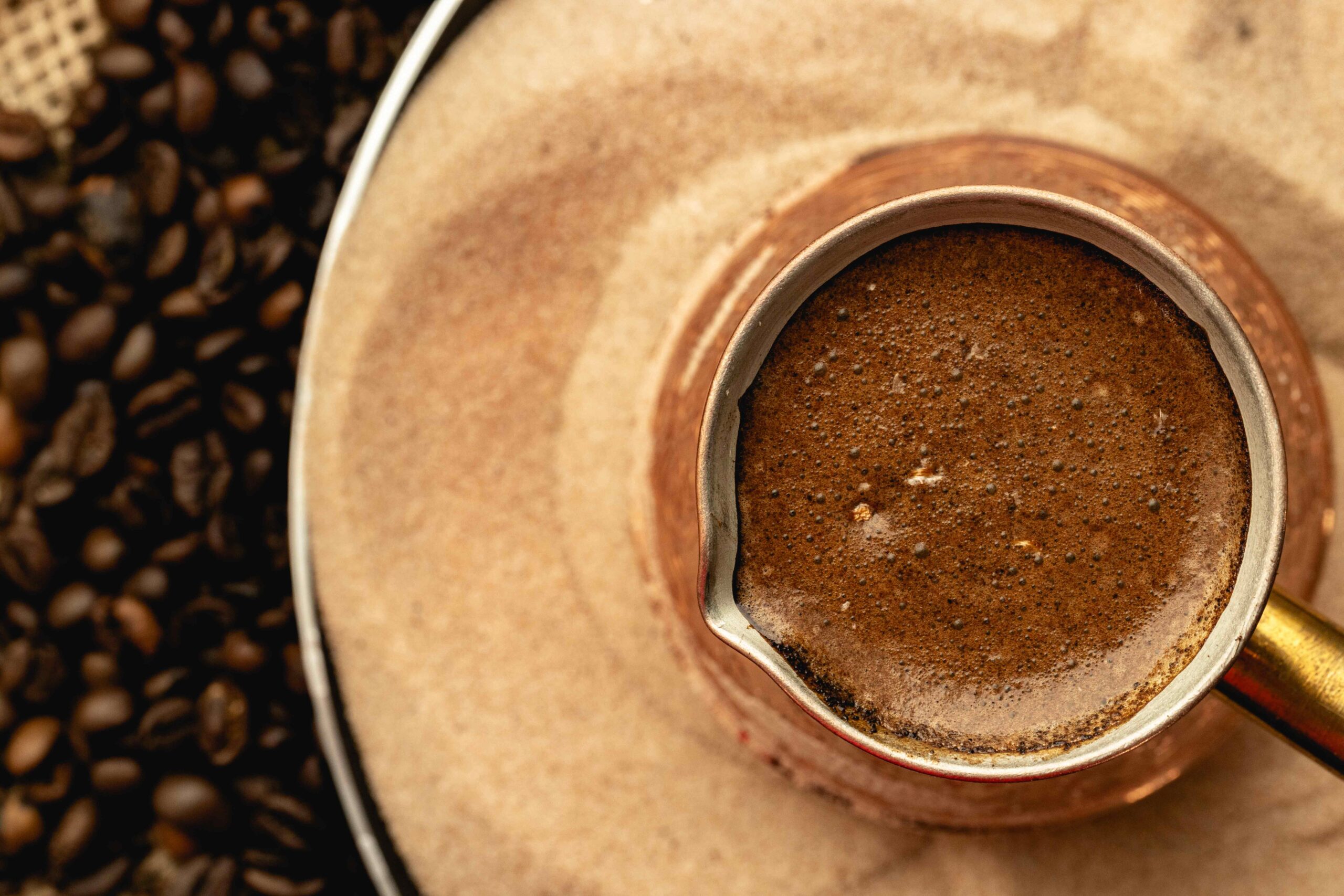 Close-up of a traditional Middle Eastern coffee pot filled with freshly brewed coffee, surrounded by coffee beans, symbolising the rise of specialty coffee in the Middle East