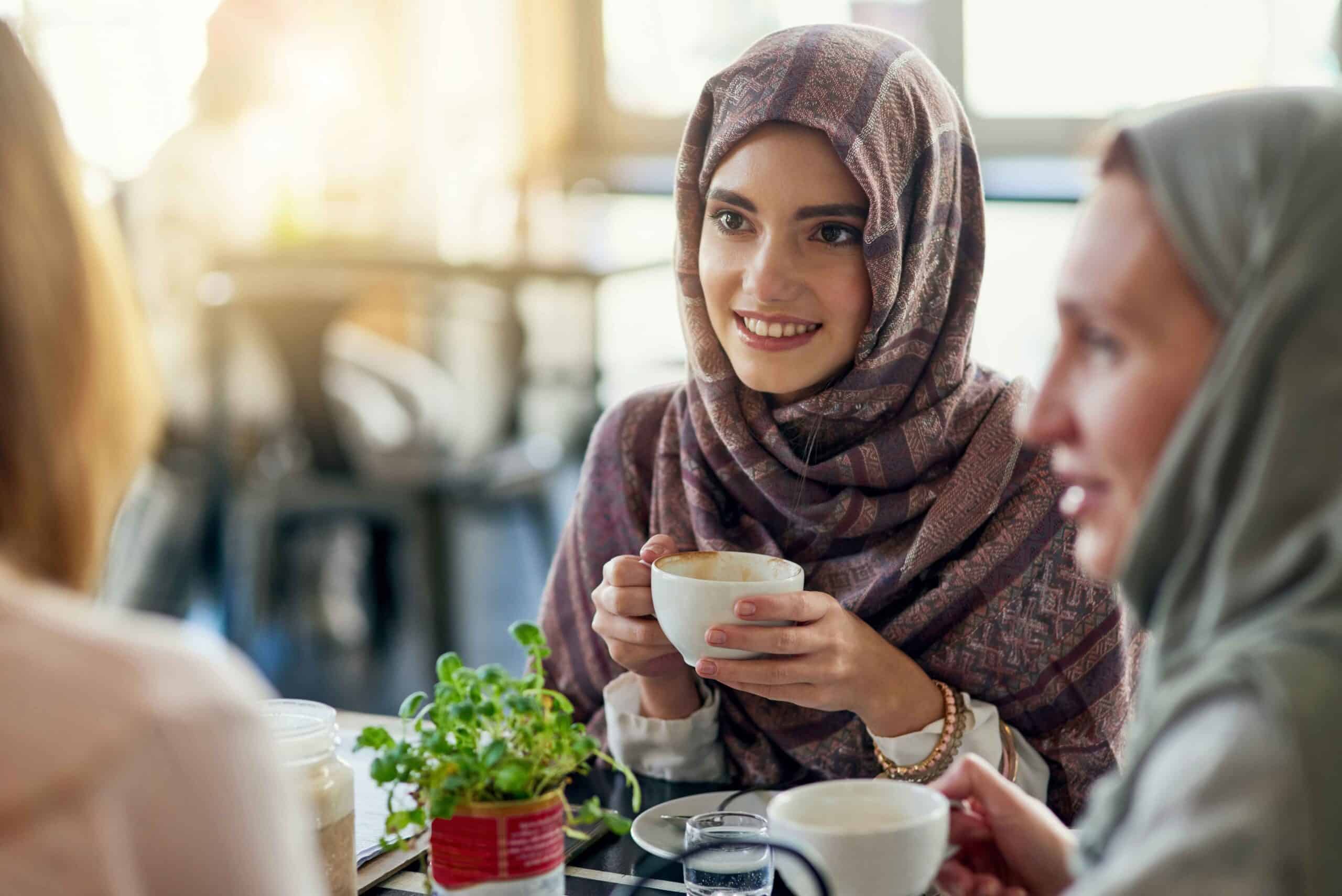 Women in traditional attire enjoying coffee together at a café, highlighting the cultural significance of coffee in Middle Eastern society