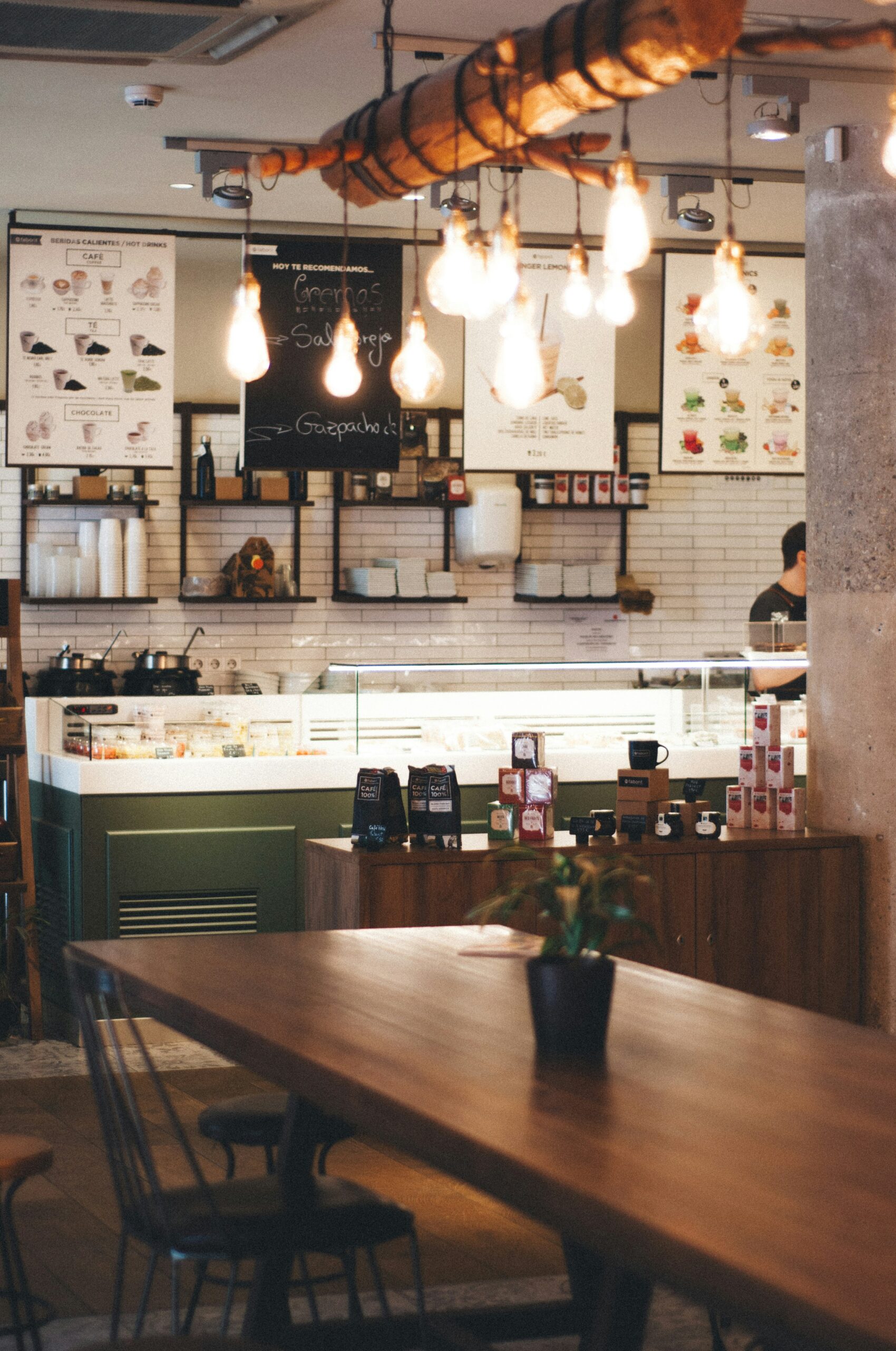 Modern café interior with warm lighting, a wooden table, and a display counter with food items, representing the operational aspects of a hospitality business. Relevant for discussions on Hospitality Accounting and café management.