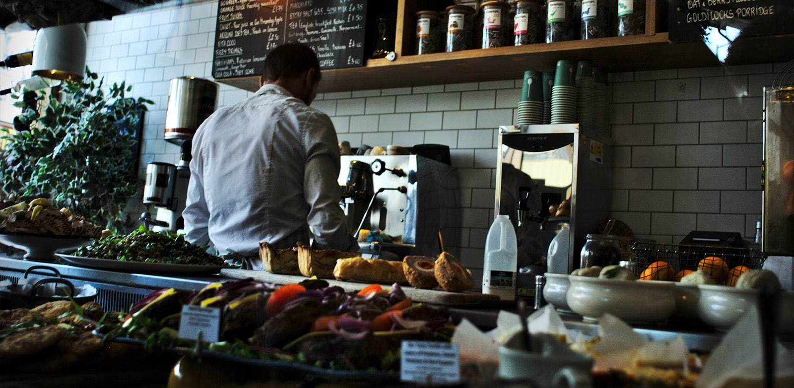 Restaurant manager working behind the counter, surrounded by food and equipment, showcasing multitasking skills essential for effective restaurant management.