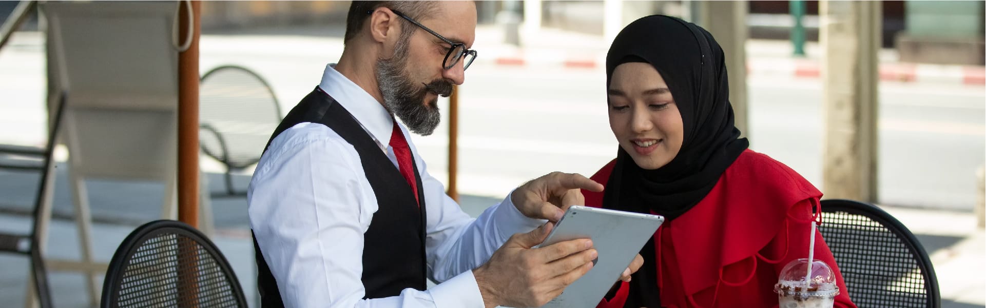 Man showing VAT details on an iPad to a UAE restaurant woman owner, illustrating a consultation on VAT and service charges in UAE hospitality